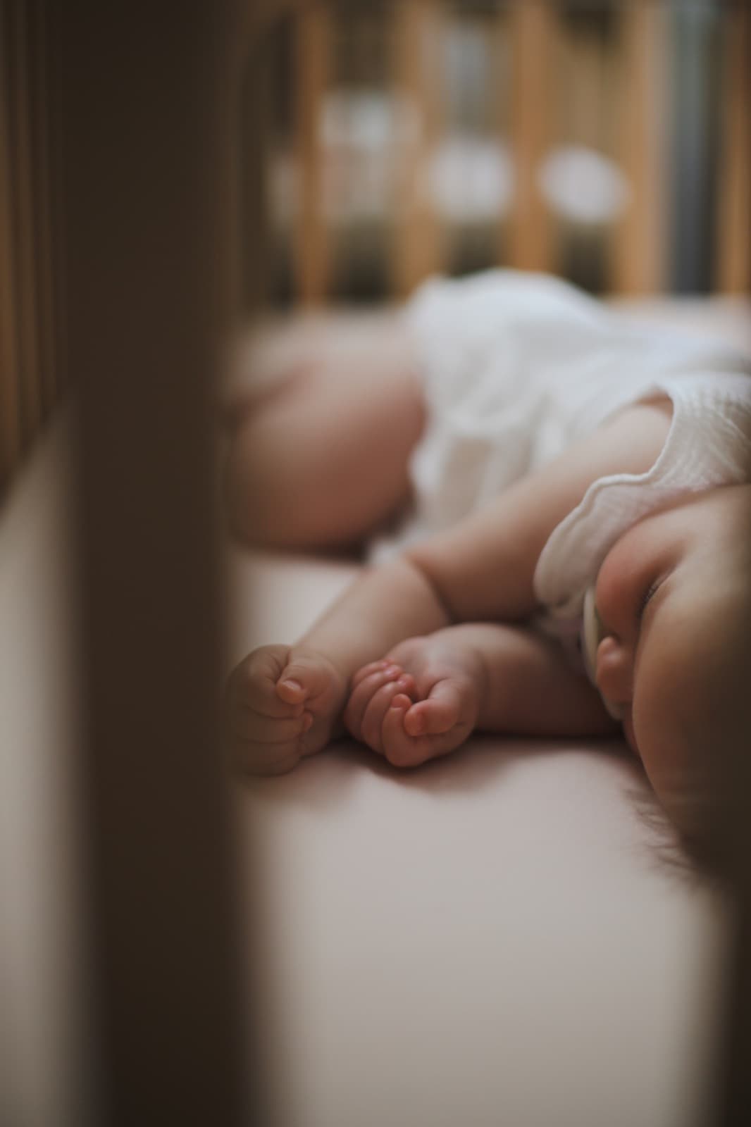 A sleeping baby seen through crib slats